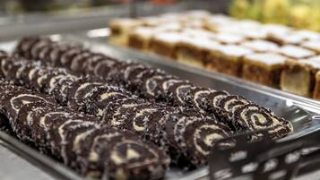 Una exhibición de varios postres, entre ellos rollos de chocolate y otras preparaciones horneadas.