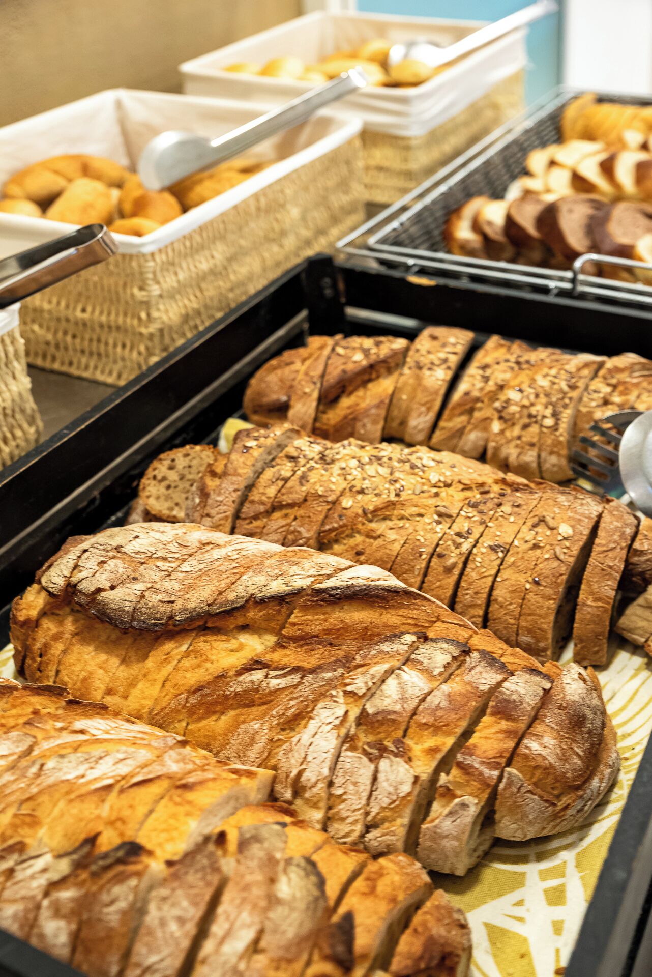 Un assortiment de pains tranchés et de viennoiseries présentés sous forme de buffet.