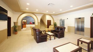A lobby with a reception desk, seating area, and elevators.