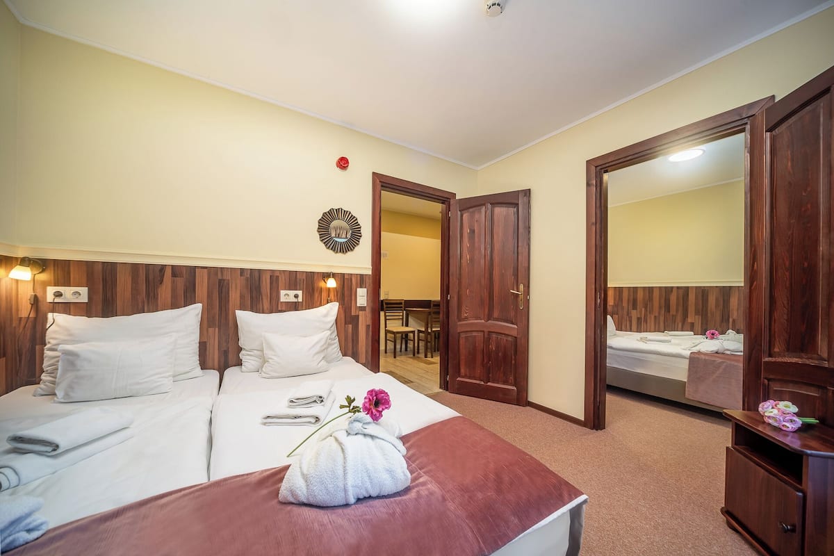 Habitación de hotel con cama, cabecera de madera, espejo y baño visible a través de una puerta abierta.