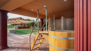 A spa area with a wooden barrel, a wooden ladder, and a shower enclosure.