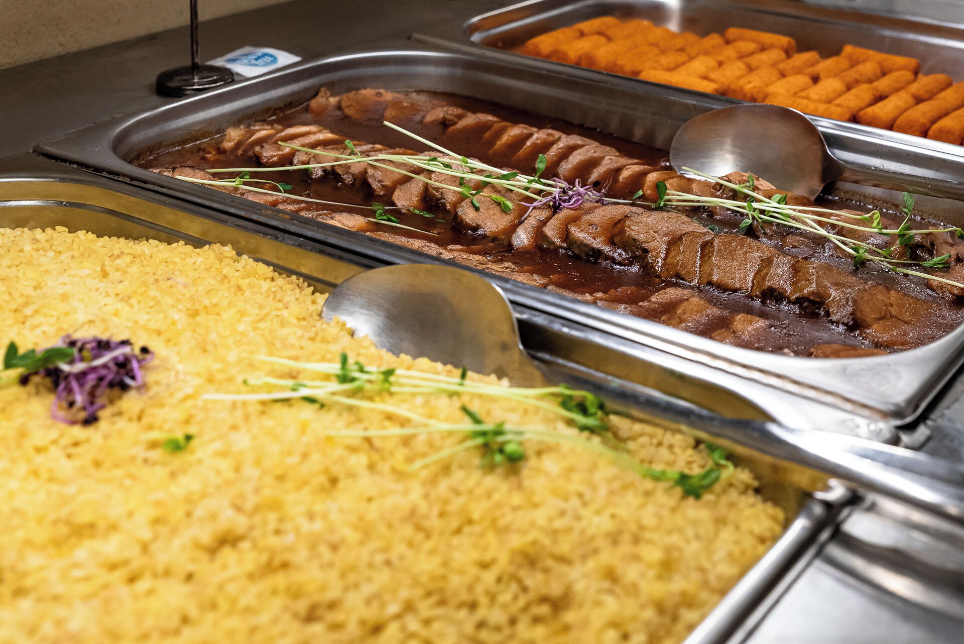 A buffet with various dishes including rice, meat, and vegetables.