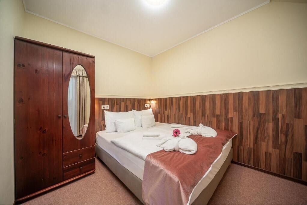 Ein Schlafzimmer mit einem Holzschrank, einem Bett mit weißer Bettwäsche und einem hölzernen Kopfteil.