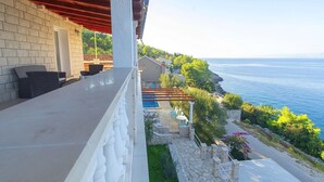 A balcony with a stone wall, outdoor seating, and a view of the sea. - House Green Side Sunset- Four Bedroom House with Pool and Sea View (Prigradica)