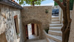 Una escalera de piedra que lleva a una puerta, con un árbol y un banco al fondo.
