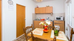Cocina compacta con armarios de madera, microondas y una pequeña encimera.