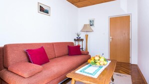 Una sala de estar con un sofá, una mesa de centro de madera con fruta, una lámpara y una puerta.