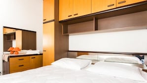 Habitación de hotel con una cama, armarios de madera y un espejo.