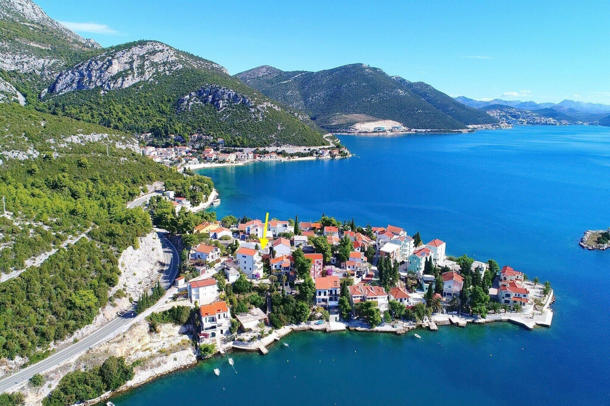 Une ville côtière avec des bâtiments le long du front de mer, une route qui serpente à travers le paysage et des montagnes en arrière-plan.