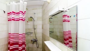 A bathroom with a shower, a mirror, and a toilet.