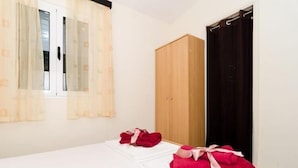 A bedroom with a bed, a wardrobe, and a window with curtains.