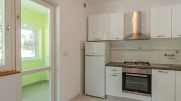Een koelkast, een oven, een kookplaat, eettafels