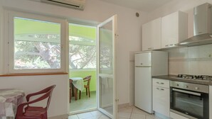 A kitchen with a gas stove, oven, and a refrigerator. There is a dining area with a table and chairs.