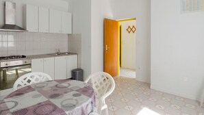 Una cocina compacta con muebles blancos, estufa a gas y piso de baldosas.
