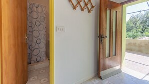 Una habitación con puerta de madera, cortina de ducha estampada y un gancho en la pared.