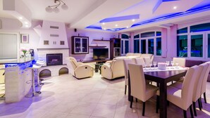 A modern living room with a dining area, a TV, and a bar.