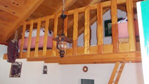 Dormitorio tipo loft con techo de madera y una lámpara colgante.
