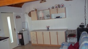 Una cocina compacta con horno integrado, un refrigerador pequeño y un microondas. Hay un comedor con una silla y una mesa.