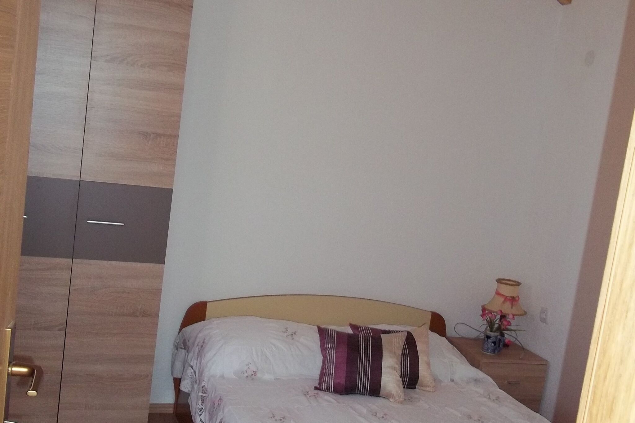 Une chambre à coucher avec un lit, une table de chevet, une lampe et une armoire.