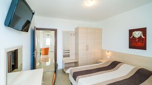 Una habitación de hotel moderna con una cama, un televisor montado en la pared, un armario y un cuadro.