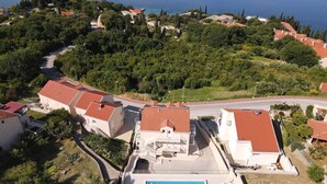 Vista aérea de una zona residencial costera con casas, una piscina y una carretera.