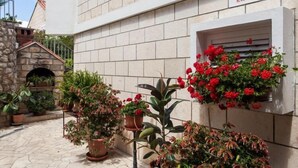 Un bâtiment avec une enseigne indiquant « MAISON D’HÔTES RAGUŽ » et des plantes en pot devant l’entrée.