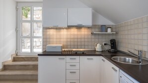 A modern kitchen with white cabinets, a stainless steel sink, and a built-in oven. - Apartments Odin - One-Bedroom Apartment with Terrace and Sea View - 4 (Dubrovnik)