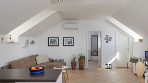 A modern living room with a sofa, a coffee table with fruit, and two potted plants. - Apartments Odin - One-Bedroom Apartment with Terrace and Sea View - 4 (Dubrovnik)