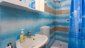 Een badkamer met een wit wastafelmeubel, een douche en blauwe betegelde wanden.