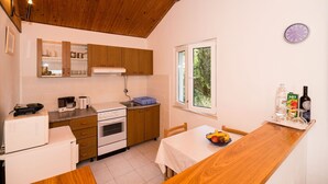 Una cocina compacta con armarios de madera, una estufa blanca y un comedor con mesa y sillas.