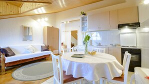 Una sala de estar acogedora con sofá, una mesa de comedor con sillas y una cocina con armarios y electrodomésticos.