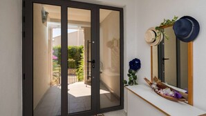 A room with a sliding glass door leading to an outdoor area, a white console table with decorative items, and a mirror with a wooden frame. - Apartment Oaza - Three Bedroom Apartment with Terrace and Sea View (Supetar)