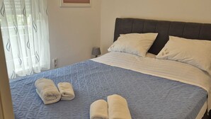 Ein ordentlich bezogenes Bett mit einer blau gemusterten Tagesdecke, zwei Kissen und zwei aufgerollten Handtüchern.