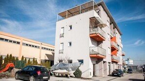 Ein modernes, mehrstöckiges Gebäude mit Balkonen, einer überdachten Garage und einem Spielplatz.