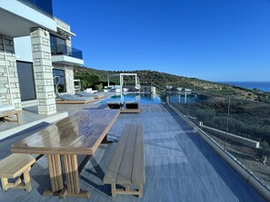 A rooftop terrace with a pool, outdoor seating, and a view of the sea.