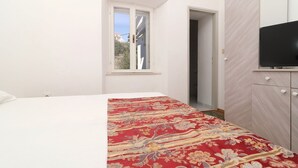 Een slaapkamer met een bed, een raam, een kledingkast en een televisie.