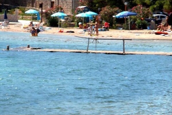 Relax by the serene waterfront pool, adjacent to a sandy beach.