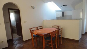 A compact kitchen with a dining area, a skylight, and a visible door leading to another room.