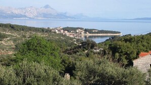 Un pueblo costero con edificios en una ladera con vistas a una masa de agua, con montañas al fondo.