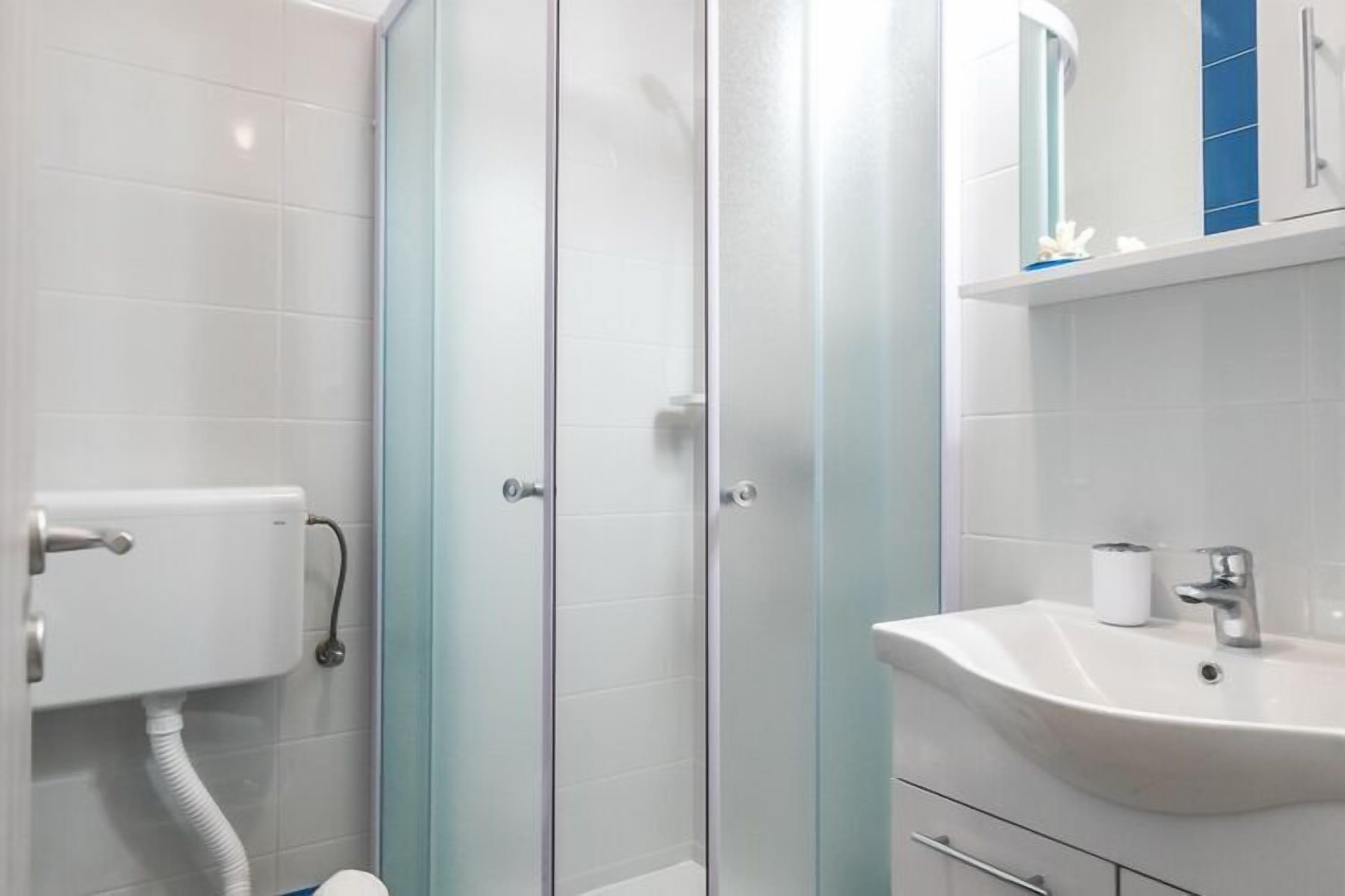 Une salle de bain moderne avec une douche à parois de verre, un lavabo blanc et des toilettes.