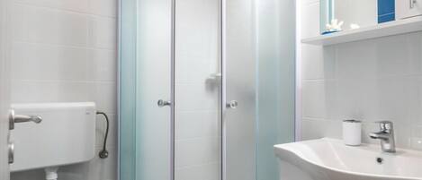 Une salle de bain moderne avec une douche à parois de verre, un lavabo blanc et des toilettes.