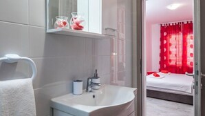 A modern bathroom with a white sink, a mirror, and a towel rack.