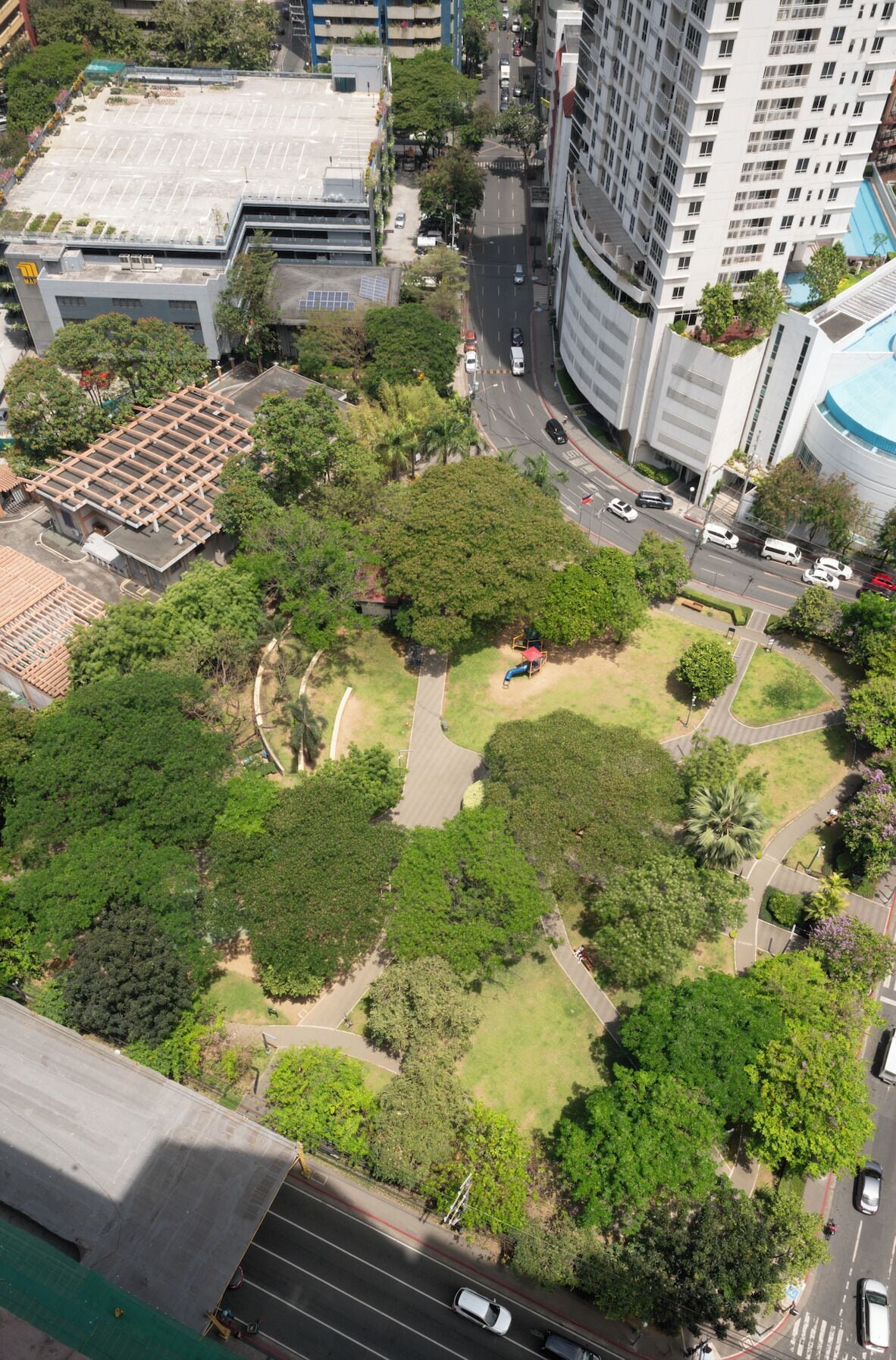 An aerial view of a park with pathways, surrounded by buildings and roads.