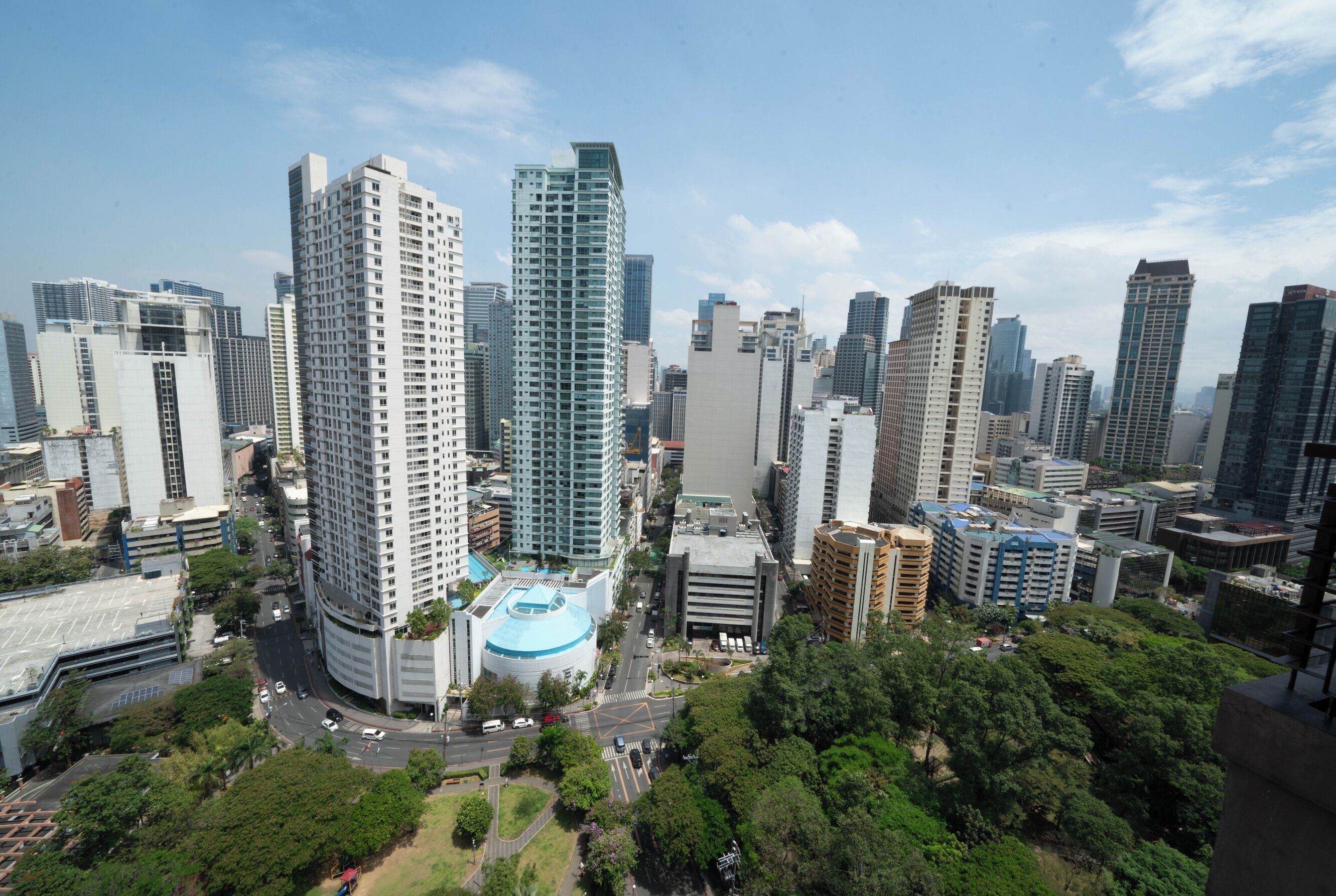A high-rise building with a distinctive blue dome and a modern design, surrounded by other tall buildings in an urban setting.