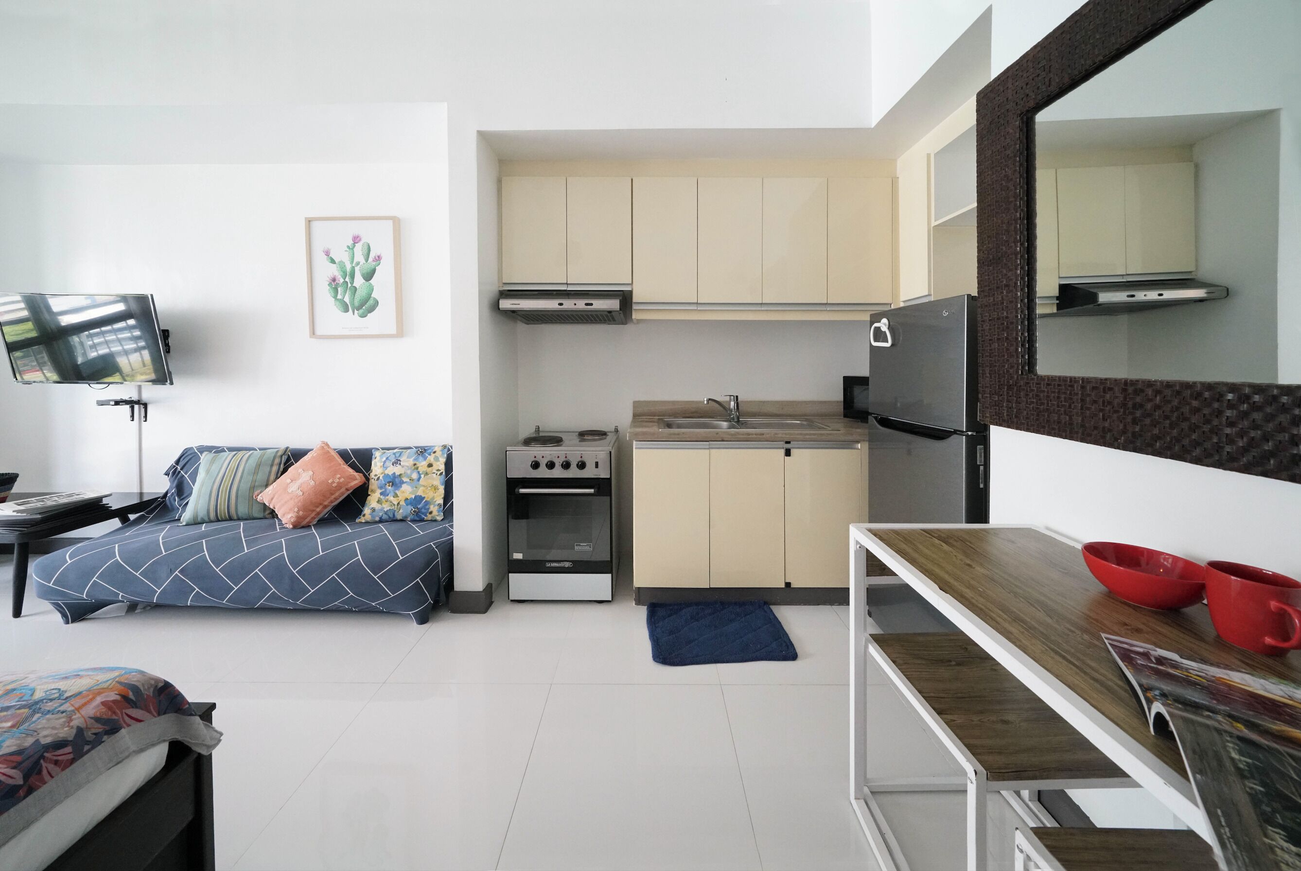 Un espacio habitable compacto con kitchenette, un sofá, televisor y comedor.