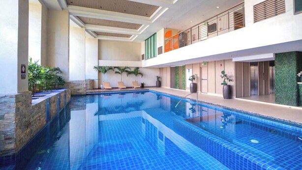 Une piscine intérieure aux carreaux bleu clair, dotée de chaises longues et agrémentée de plantes en pot.