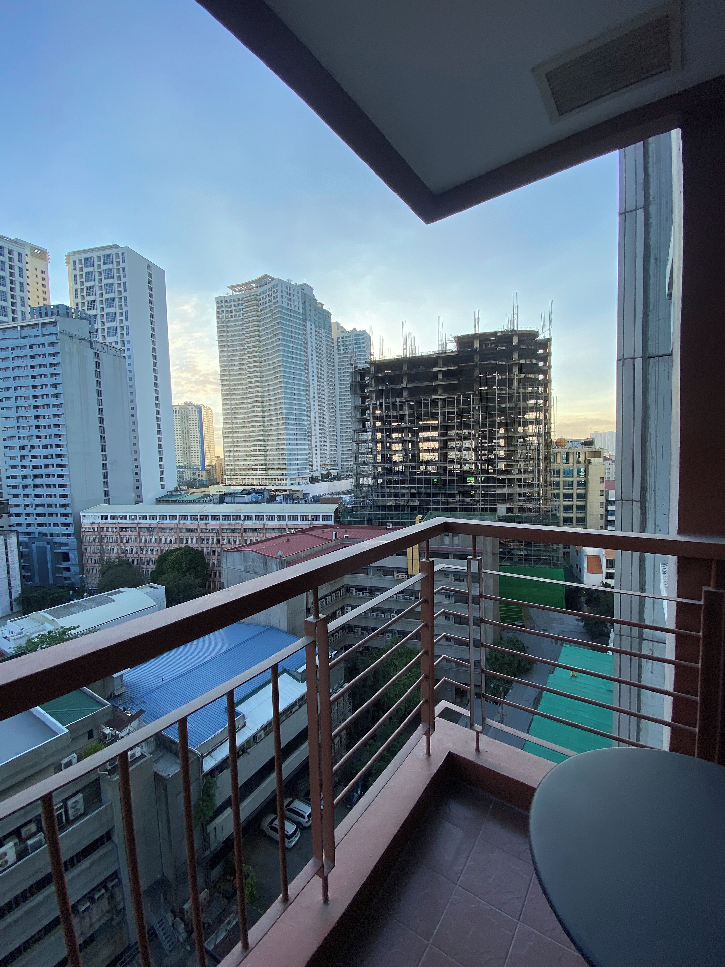 A balcony with a view of a cityscape, including high-rise buildings and a construction site.