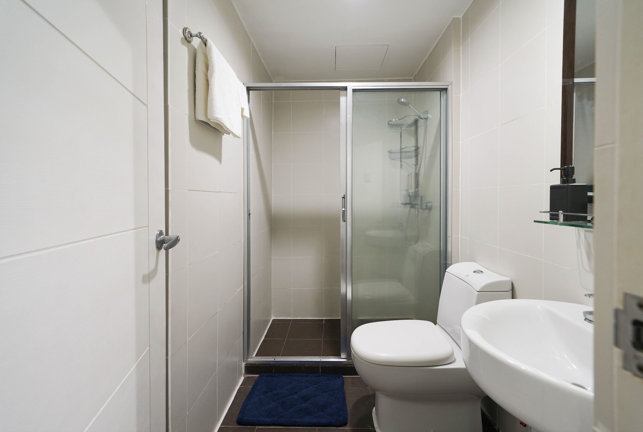 A compact bathroom with a glass-enclosed shower, a white toilet, and a sink.