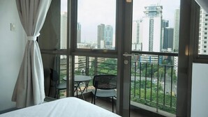 Une chambre d’hôtel avec un grand balcon, un lit, une table et deux chaises.