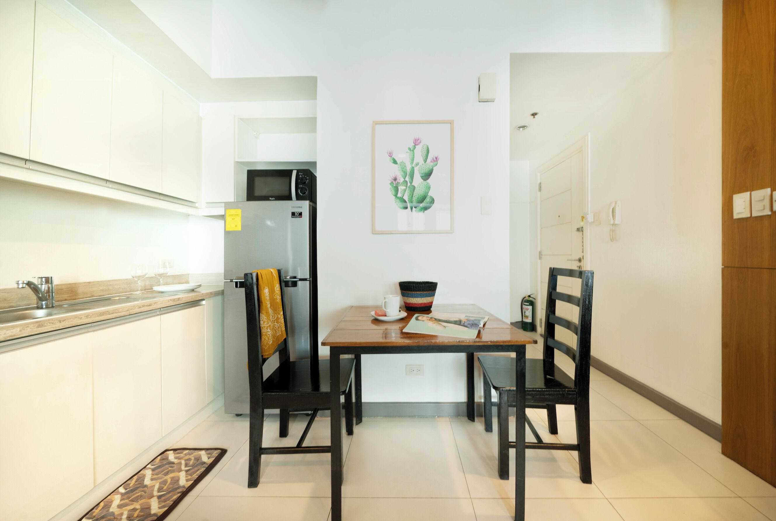 A modern kitchen with white cabinets, a refrigerator, and a dining table with chairs.